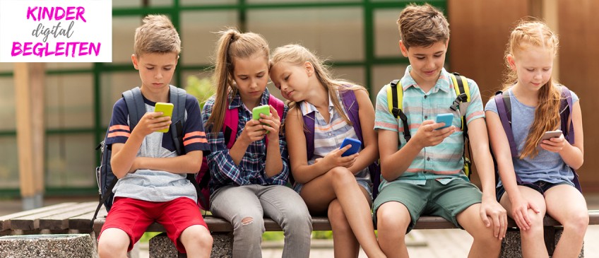 Kinder digital begleiten - Mehrere Kinder sitzen mit Smartphones auf einer Bank